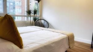 a white bed in a room with a window at Deustown Apartamentos in Bilbao