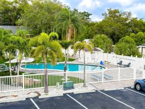a pool with palm trees and a white fence at 2b1b Stylish Little House W Shared Pool 511 in Clearwater