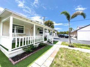 a white house with a porch and palm trees at 2b1b Stylish Little House W Shared Pool 511 in Clearwater