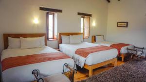 1 dormitorio con 2 camas y 2 sillas en Lizzy Wasi Urubamba, en Urubamba