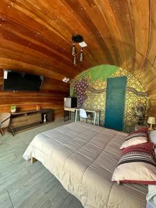 ein Schlafzimmer mit einem großen Bett in einem Zimmer mit Holzwänden in der Unterkunft GLAMPING TONELES Y VIÑEDOS in San Juan Bautista