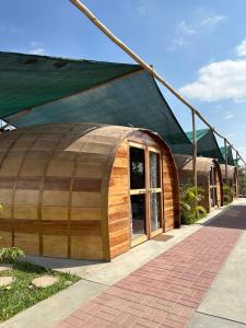 a wooden barrel house with a green roof at GLAMPING TONELES Y VIÑEDOS in San Juan Bautista