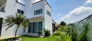 a white house with a palm tree in front of it at Casa con alberca privada y agradable jardín in Oaxtepec