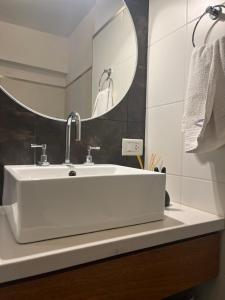 La salle de bains est pourvue d'un lavabo blanc et d'un miroir. dans l'établissement Departamento centrico excelente ubicacion Bahia Blanca, à Bahía Blanca