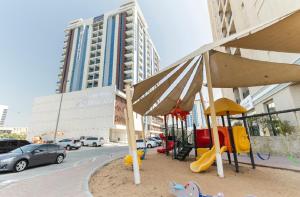 un parco giochi in una strada cittadina con un edificio di Bright & Cozy, Near Metro & Downtown, Pool, Gym a Dubai