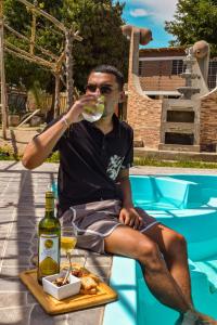 un hombre bebiendo una copa de vino junto a una piscina en GLAMPING TONELES Y VIÑEDOS, en San Juan Bautista