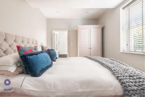 a bedroom with a large white bed with blue pillows at The Old Office in Royal Tunbridge Wells
