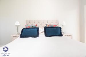 uma cama branca com duas almofadas azuis em The Old Office em Royal Tunbridge Wells