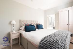 a white bedroom with a large bed with two blue pillows at The Old Office in Royal Tunbridge Wells