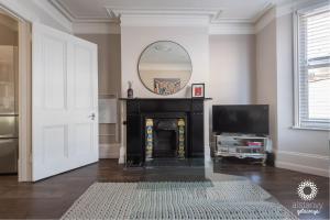 a living room with a fireplace and a mirror at The Old Office in Royal Tunbridge Wells