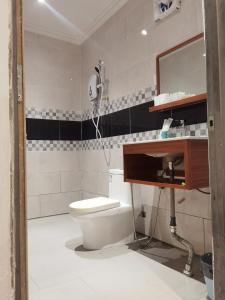 a bathroom with a toilet and a sink and a mirror at Hemingway Cottage 海明威度假屋 in Semporna
