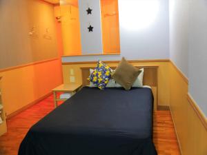 a small room with a bed with pillows on it at HOTEL 紅-bin- in Okinawa City