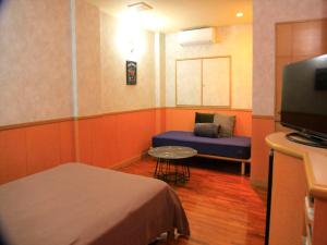 a small room with a bed and a tv at HOTEL 紅-bin- in Okinawa City