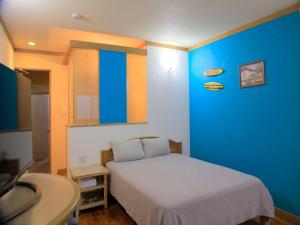 a bedroom with a bed and a blue wall at HOTEL 紅-bin- in Okinawa City