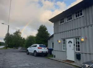 a white car parked next to a building with a rainbow at Holiday Rooms in Gol