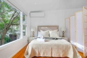 a white bedroom with a bed and a large window at Victorian Dream Terrace CBD in Sydney