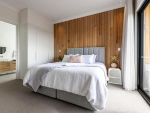 a bedroom with a large bed with a wooden wall at Benbullen Pavilions in Angaston