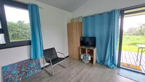 ein Wohnzimmer mit blauen Vorhängen und einem TV in der Unterkunft TAHITI ITI - Bungalow O Spot Teahupoo in Teahupoo