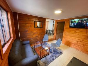 sala de estar con sofá y TV en Cabaña en Boscoso Lodge en Pucón