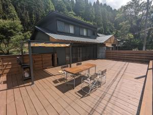 una terraza con mesa y sillas y una casa en LOOP-shiso en Shiso