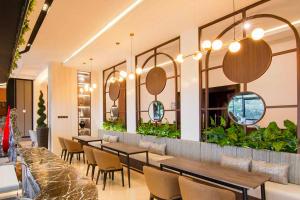 un restaurante con mesas, sillas y plantas en Grand Rocky Hotel Bukittinggi en Bukittinggi