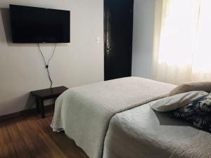 a bedroom with a bed and a flat screen tv at Hostel Recanto Aurora in Petrópolis