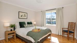 Un dormitorio con una cama y una silla y una ventana. en Bluebird Cottage, en Bowral
