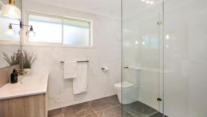 a bathroom with a toilet and a glass shower at Bluebird Cottage in Bowral