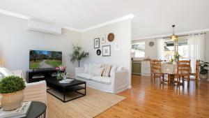 Una sala de estar con un sofá blanco y una mesa. en Bluebird Cottage, en Bowral