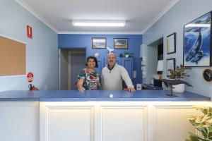 een man en een vrouw die achter een blauwe balie staan bij City Heart Motel Warrnambool in Warrnambool