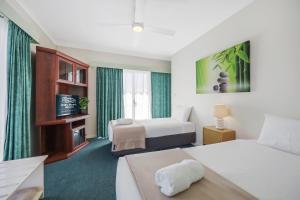 una camera d'albergo con due letti e un divano di City Heart Motel Warrnambool a Warrnambool