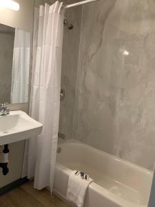 ein Badezimmer mit einem Waschbecken, einer Badewanne und einer Dusche in der Unterkunft Big 7 Motel in Chula Vista