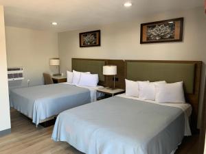 Habitación de hotel con 2 camas y almohadas blancas en Big 7 Motel, en Chula Vista