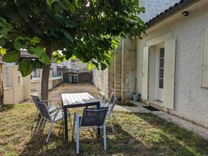 stół i krzesła na dziedzińcu obok budynku w obiekcie Maison charentaise rénovée avec jardin privé, proche d'Angoulême et activités en bord de Charente - FR-1-653-208 w mieście Vindelle