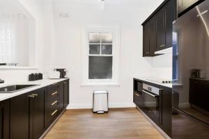 a kitchen with black cabinets and a window at Sydney CBD Waterview apartment 56 in Sydney