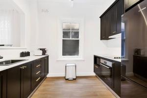 a kitchen with black cabinets and a window at Sydney CBD Waterview apartment56 in Sydney