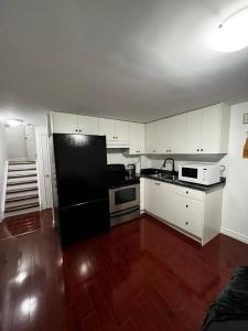 a kitchen with a black refrigerator and white cabinets at 1 bedroom with private entrance in Ajax