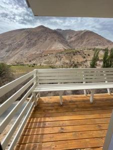a white bench sitting on a wooden deck with mountains at Casa Montegrande in Monte Grande