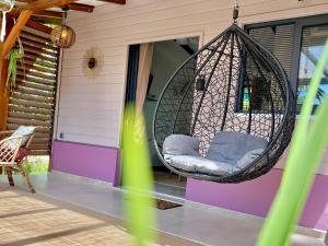 a swing hanging from the front porch of a house at Cocon des jardins - Bungalow & SPA in Gros-Morne