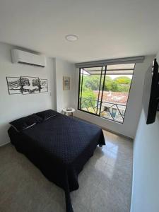 um quarto com uma cama e uma grande janela em Hermoso ApartaEstudio Centrico em Cartago