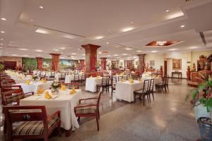 a dining room with white tables and chairs at Angkor Paradise Hotel in Siem Reap