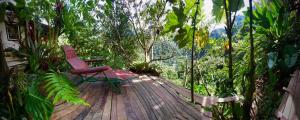 une chaise rouge assise sur une terrasse en bois dans la forêt dans l'établissement Refugio Natural Jacaranda CON PLAYA PRIVADA, à Cocorná