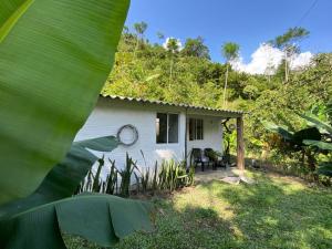 une maison blanche avec une horloge sur son côté dans l'établissement Refugio Natural Jacaranda CON PLAYA PRIVADA, à Cocorná