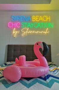 a pink toy swan on a bed with a sign at Sirena Beach Chic Staycation at Azure Paris Beach Club in Manila