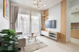 uma sala de estar com uma televisão, um sofá e uma mesa em TeeUp Home - Infinity Pool Signature em Ho Chi Minh