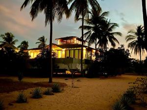 una casa en la playa con palmeras delante en Vandalous Bay, en Pasikuda