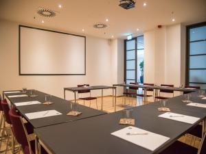 einen Konferenzraum mit Tischen und einer Leinwand in der Unterkunft Hotel Alte Post Flensburg in Flensburg