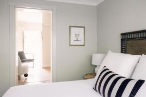 a white bedroom with a bed and a chair at Links House in Bowral