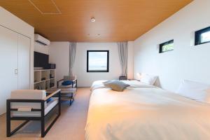 a bedroom with a large bed and a chair at セトノウツツ in Suo Oshima