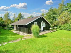 una pequeña casa verde con terraza de madera en un patio en Holiday home Græsted XI, en Græsted